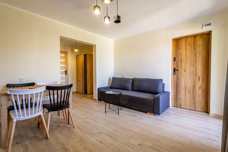 Część dzienna apartamentu ze stołem, sofą i aneksem kuchennym