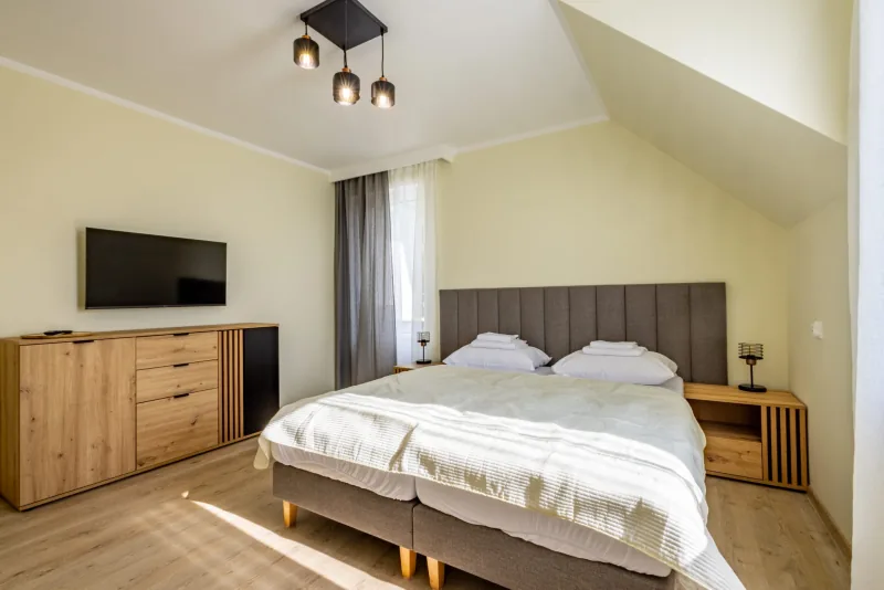 Sypialnia mniejszego apartamentu z podwójnym łóżkiem i drewnianymi meblami