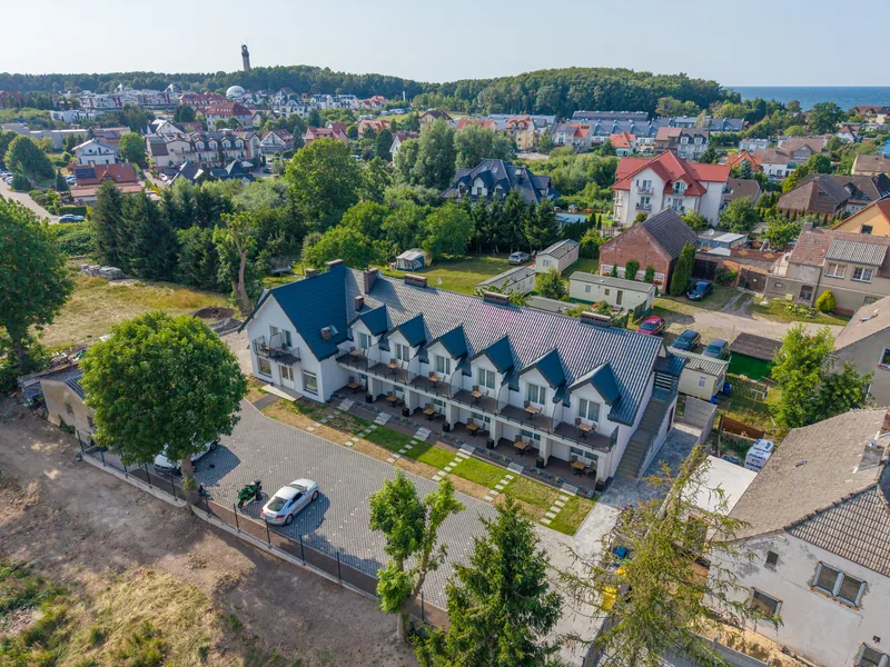 Widok z drona na długi biały budynek Słonecznych Tarasów i zabudowę Niechorza